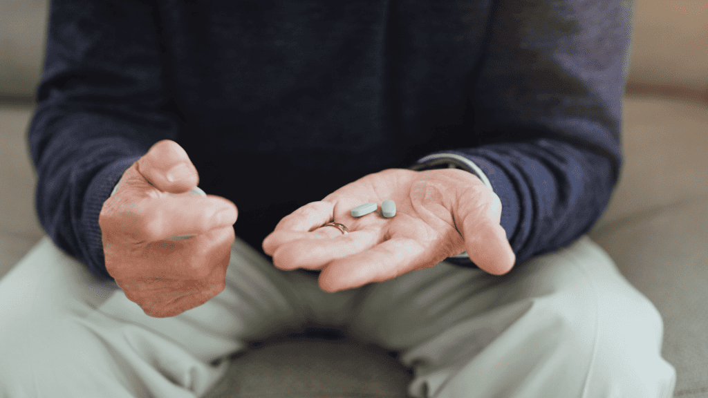 Close up of a man sitting with pills in his hand ready to take his medicine