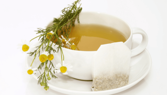 A cup of chamomile tea with chamomile flowers on a white background