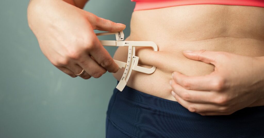 Woman Measuring Her Body Skin Fat with Fat Caliper
