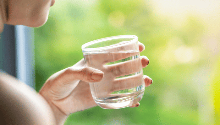 Woman Drinking Fresh and Clean Water in the Morning - Close-Up of Her Hand Holding a Glass