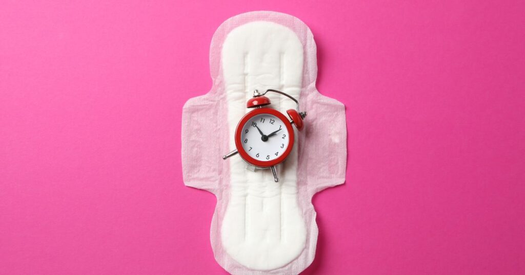 Sanitary Pad with Alarm Clock on Pink Background, Top View