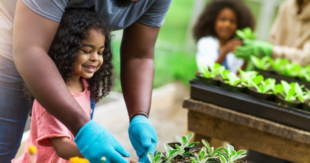 African American parents teaching children to take care of plants at plant nursery